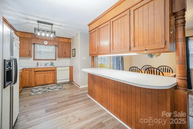 a kitchen with kitchen island granite countertop a stove top oven a sink and dishwasher with wooden floor