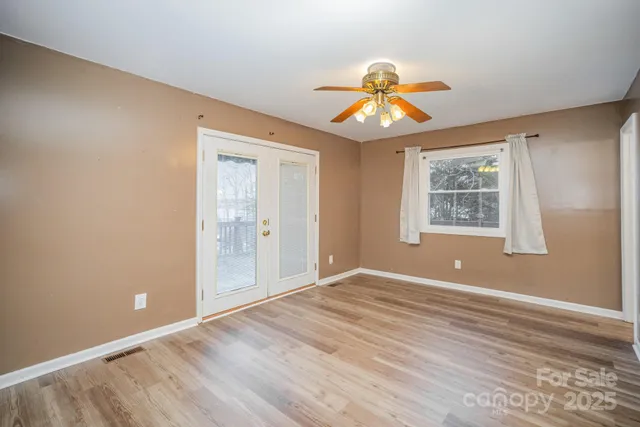 a view of an empty room with window and wooden floor
