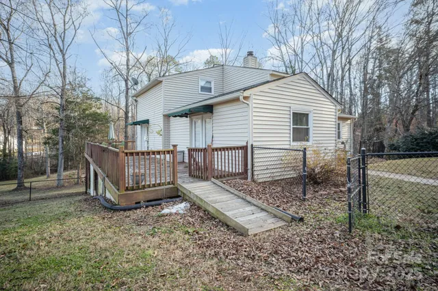 a white house that has a small yard and large trees