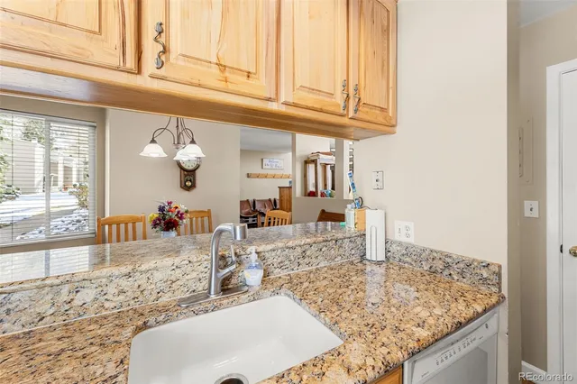 a kitchen with granite countertop a sink and a white wooden cabinets