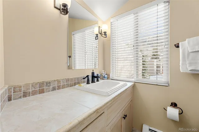 a bathroom with a granite countertop sink and a window