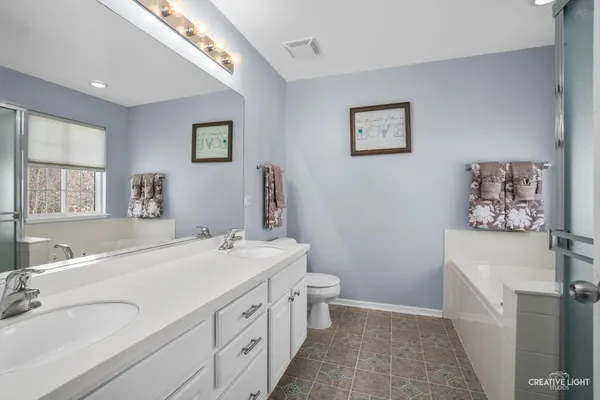 a spacious bathroom with 2 sink tub and a mirror