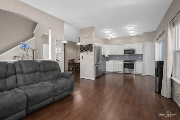 a living room with stainless steel appliances furniture and a kitchen view