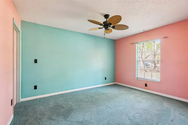 an empty room with windows and fan