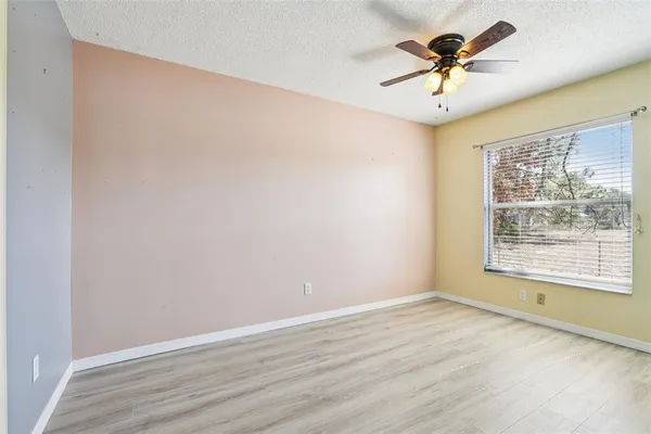 an empty room with a window and a ceiling fan