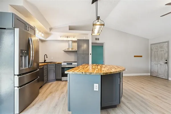 a kitchen with stainless steel appliances granite countertop a refrigerator a sink dishwasher a stove and white cabinets with wooden floor