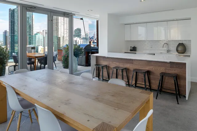 a kitchen with stainless steel appliances granite countertop a stove a refrigerator a sink a dining table and chairs with wooden floor