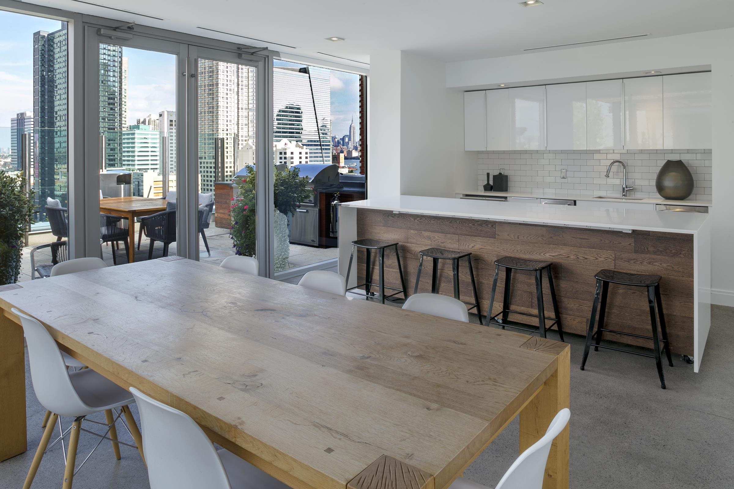 148 1st Street, Unit 809 Jersey City, NJ 07302 - Photo 12 of 20 a kitchen with stainless steel appliances granite countertop a stove a refrigerator a sink a dining table and chairs with wooden floor