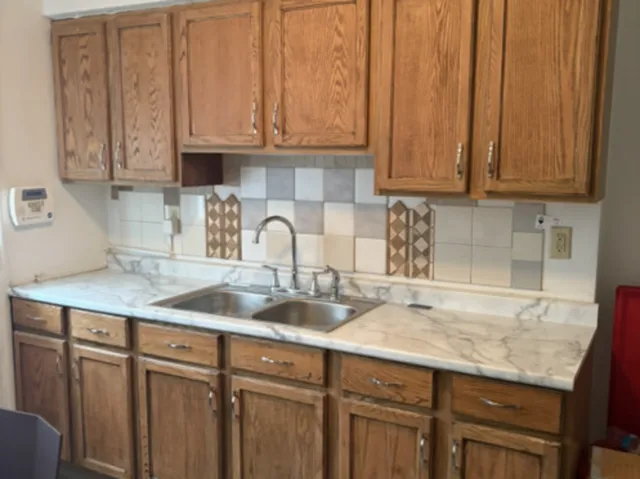 a kitchen with granite countertop a sink dishwasher a stove and cabinets with wooden floor