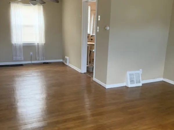 an empty room with wooden floor and windows