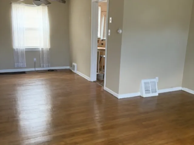 an empty room with wooden floor and windows
