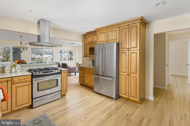a kitchen with a refrigerator a stove and wooden floor