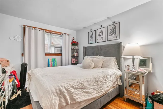 a bedroom with a bed a dresser and a large window