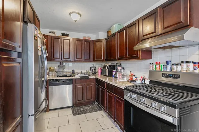 a kitchen with stainless steel appliances granite countertop a stove top oven a refrigerator and cabinets