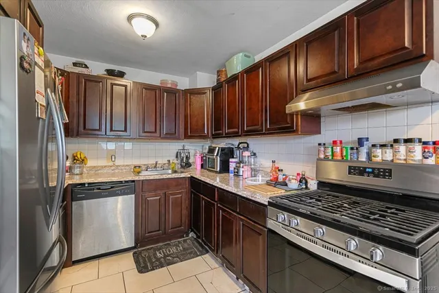 a kitchen with stainless steel appliances granite countertop a stove top oven a sink dishwasher and cabinets with wooden floor