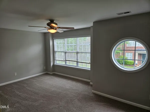 an empty room with windows and fan