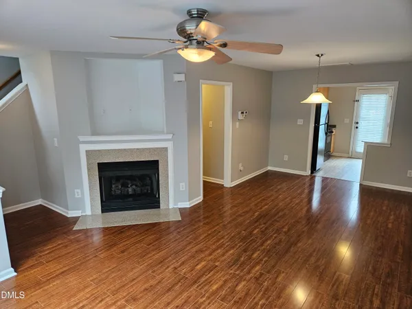 a view of an empty room with wooden floor a fireplace
