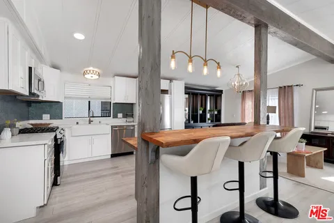 a kitchen with stainless steel appliances granite countertop a stove a sink dishwasher and a refrigerator with wooden floor