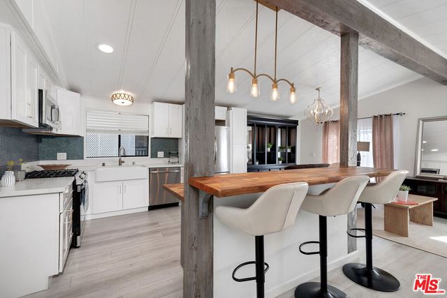 a kitchen with stainless steel appliances granite countertop a stove a sink dishwasher and a refrigerator with wooden floor