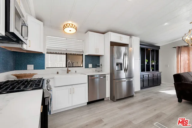 a kitchen with stainless steel appliances granite countertop a refrigerator a stove a sink and a refrigerator