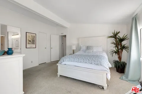 a spacious bedroom with a bed and a potted plant
