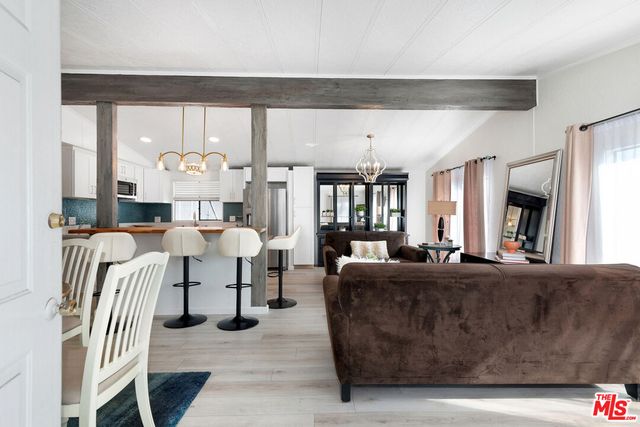 a living room with furniture kitchen view and a large window