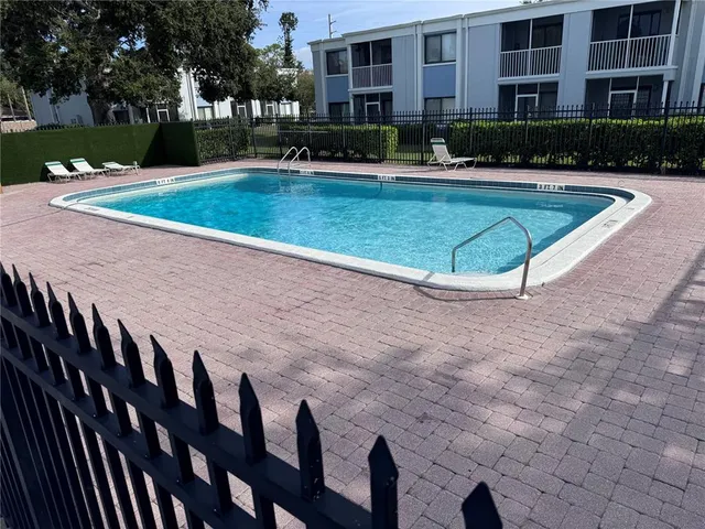 a view of a swimming pool with a lounge chairs in front of a house