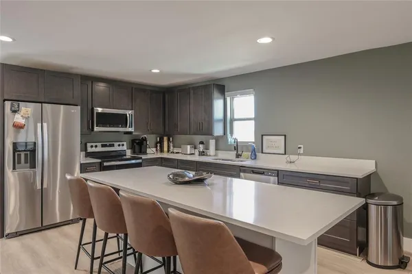 a kitchen with a dining table chairs refrigerator and microwave