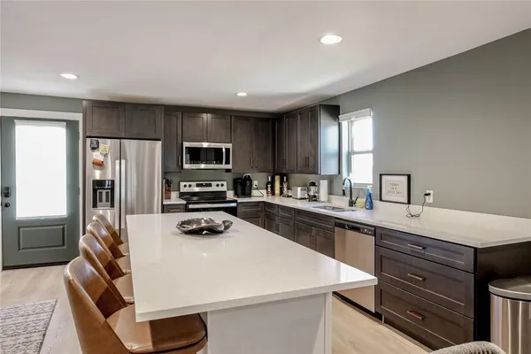 a kitchen with a refrigerator a stove a sink and dishwasher with wooden floor