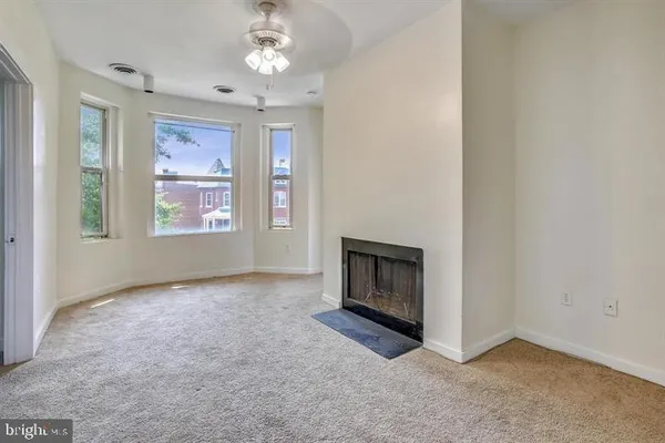 an empty room with windows and fireplace