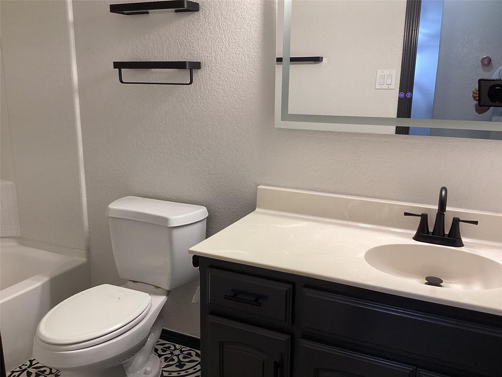 10320 Point Lobos Trail Fort Worth, TX 76177 - Photo 29 of 33 Contemporary bathroom featuring a dark wood-finish vanity with a white countertop and integrated sink, a matte black faucet, and a large illuminated mirror