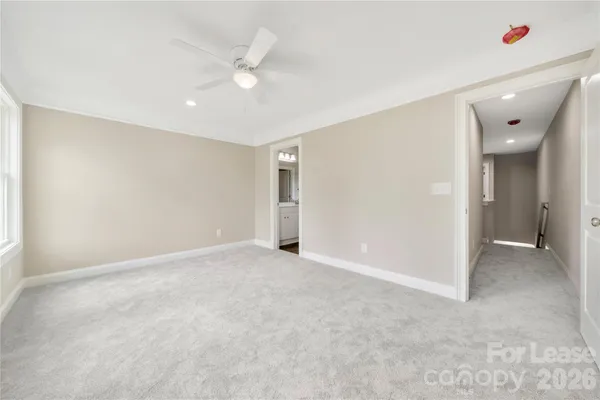 an empty room with a chandelier fan and windows