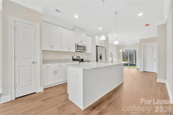 a large white kitchen with kitchen island a sink a center island stainless steel appliances and a cabinets
