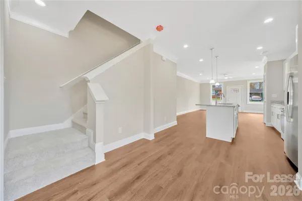 a kitchen with stainless steel appliances granite countertop a refrigerator a sink dishwasher a stove and white cabinets with wooden floor