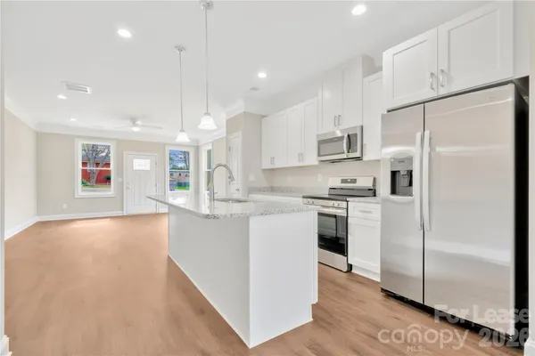 a kitchen with stainless steel appliances granite countertop white cabinets and a stove