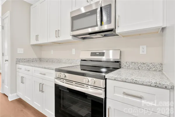 a kitchen with stainless steel appliances granite countertop white cabinets and a sink