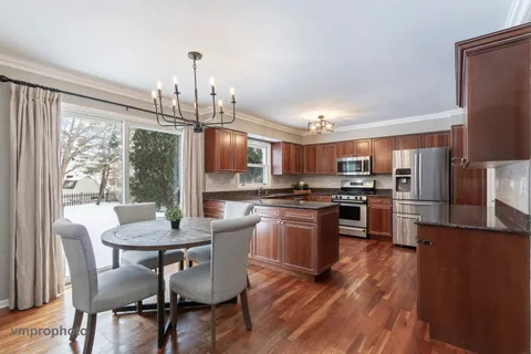 a kitchen with stainless steel appliances a dining table chairs stove refrigerator and microwave