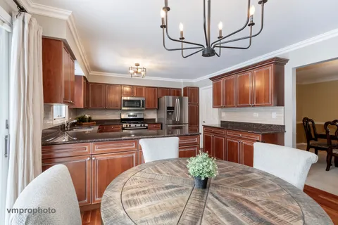 a kitchen with stainless steel appliances granite countertop a stove sink refrigerator dining table and chairs