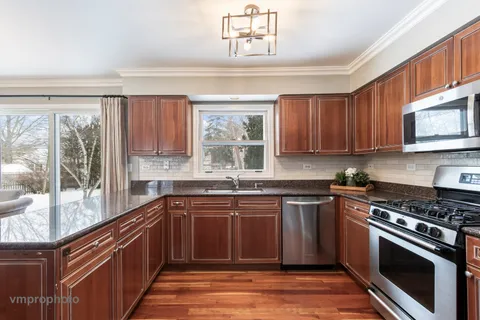a kitchen with stainless steel appliances granite countertop wooden cabinets stove top oven and sink