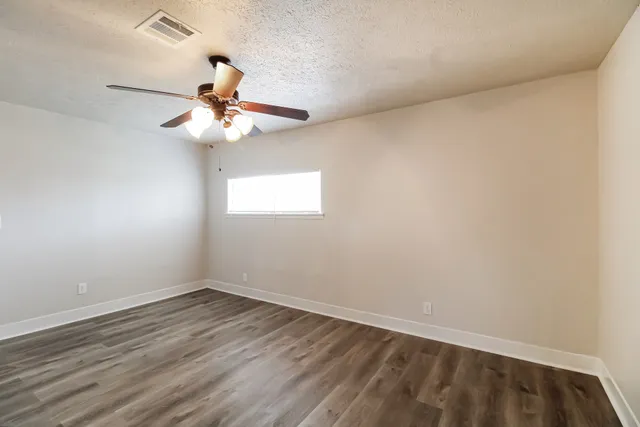 a view of a room with wooden floor and ceiling fan