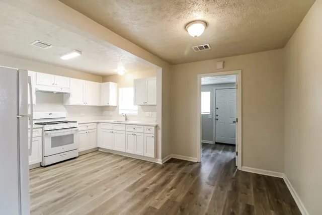 a kitchen with granite countertop white cabinets and white appliances