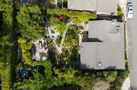 an aerial view of residential house with outdoor space and trees all around
