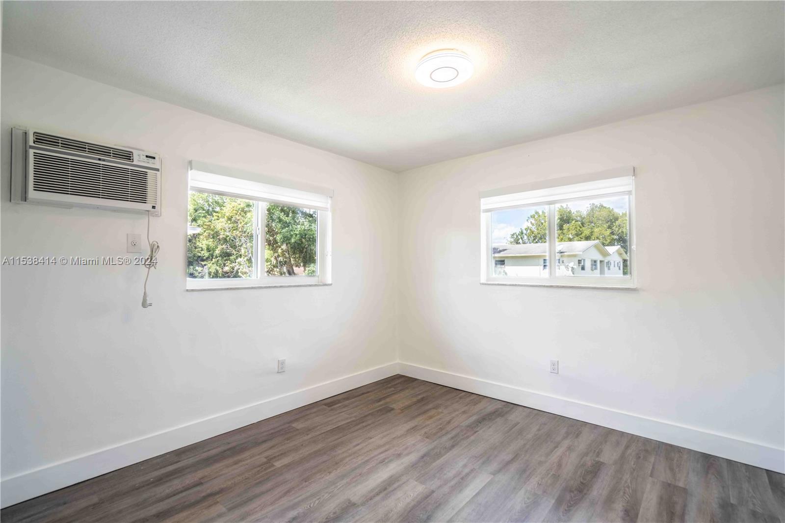 1945 Northwest 29th Street, Unit 8 Miami, FL 33142 - Photo 20 of 31 a view of an empty room with wooden floor and a window