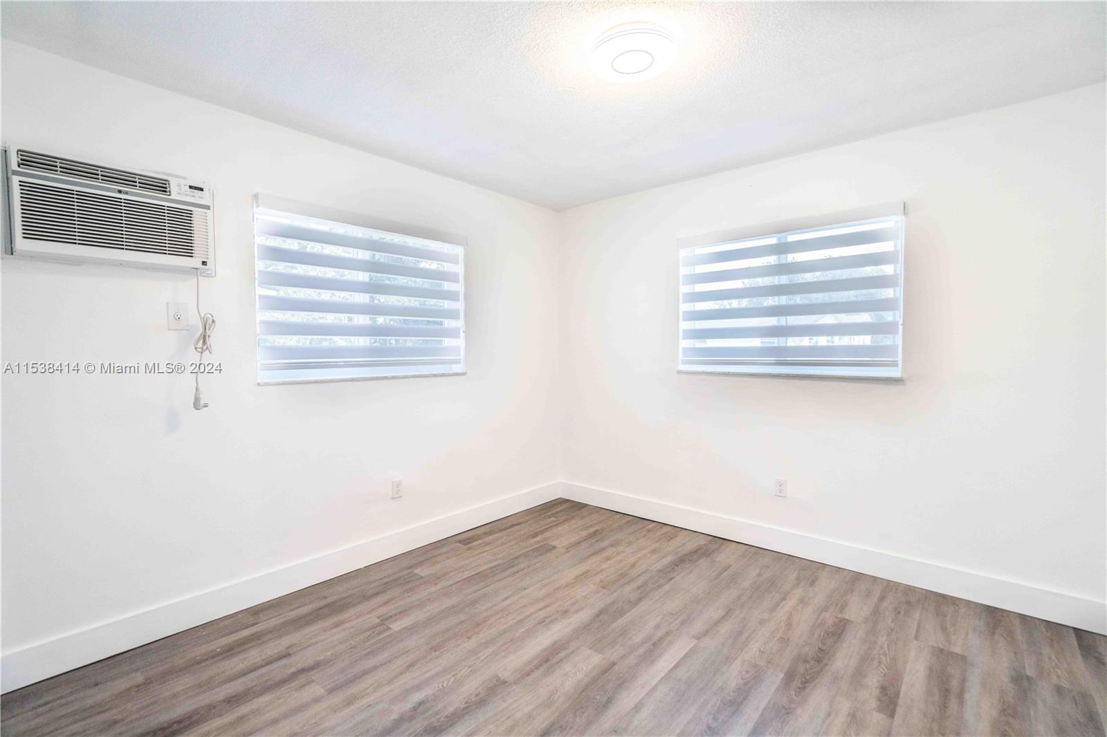 1945 Northwest 29th Street, Unit 8 Miami, FL 33142 - Photo 21 of 31 an empty room with wooden floor and windows