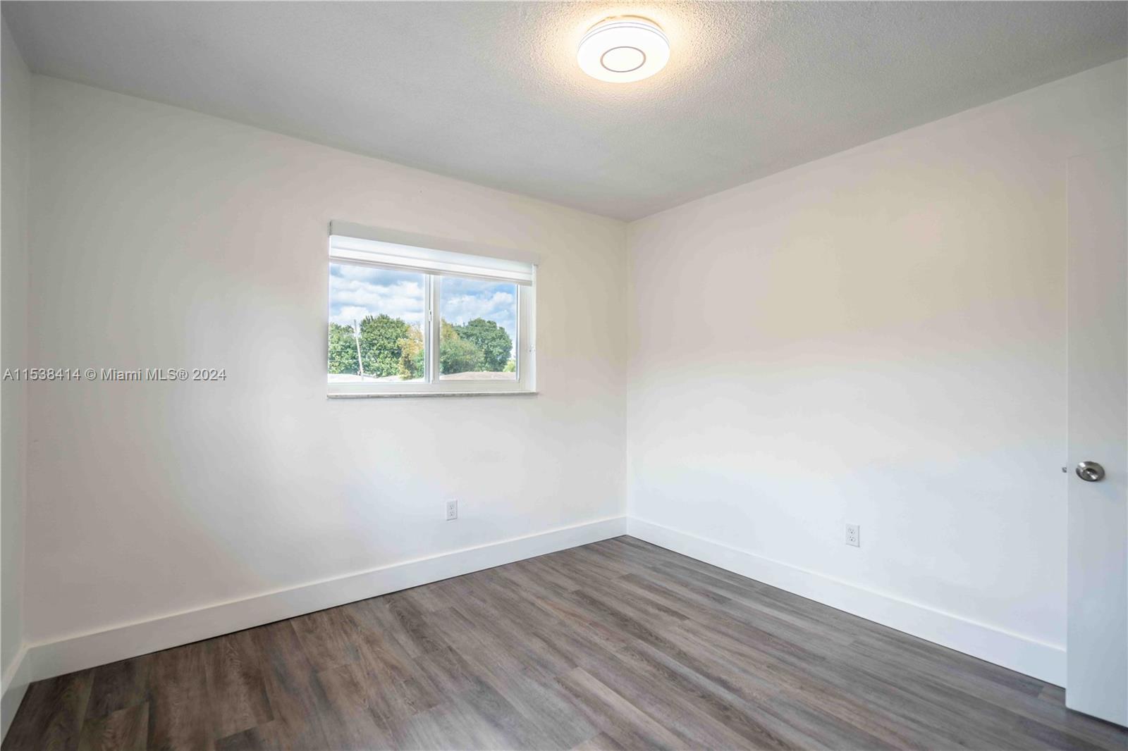 1945 Northwest 29th Street, Unit 8 Miami, FL 33142 - Photo 25 of 31 an empty room with wooden floor and window