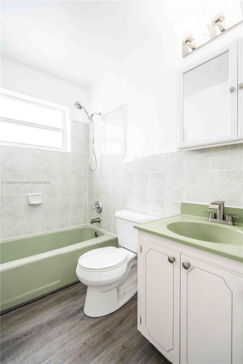 1945 Northwest 29th Street, Unit 8 Miami, FL 33142 - Photo 27 of 31 a bathroom with a granite countertop toilet a sink and a bathtub