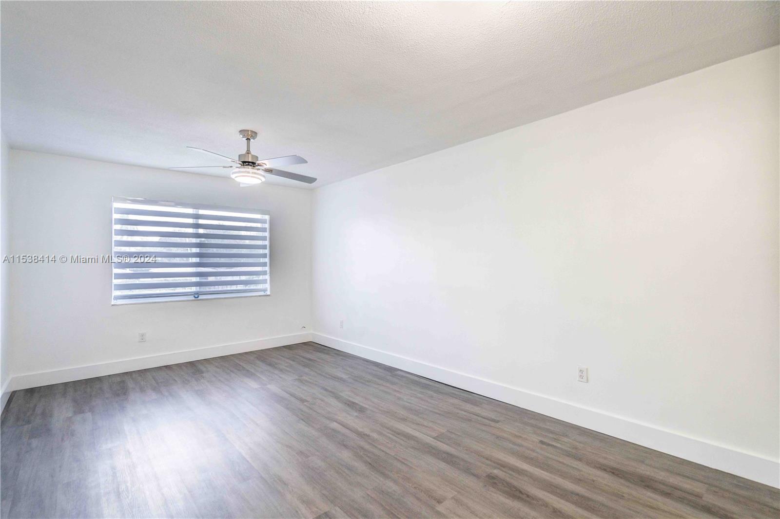 1945 Northwest 29th Street, Unit 8 Miami, FL 33142 - Photo 7 of 31 a view of an empty room with wooden floor and a window