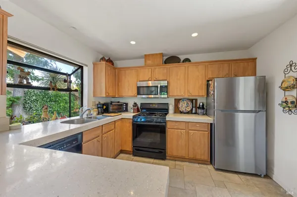 a kitchen with a refrigerator a stove top oven a sink and a large window