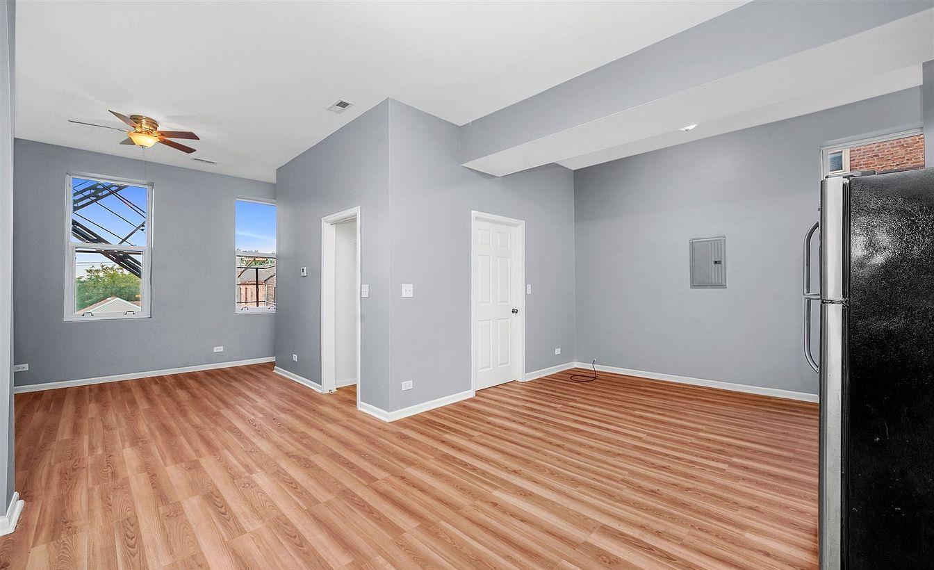 1140 West 18th Street Chicago, IL 60608 - Photo 2 of 5 a view of an empty room with wooden floor and a window