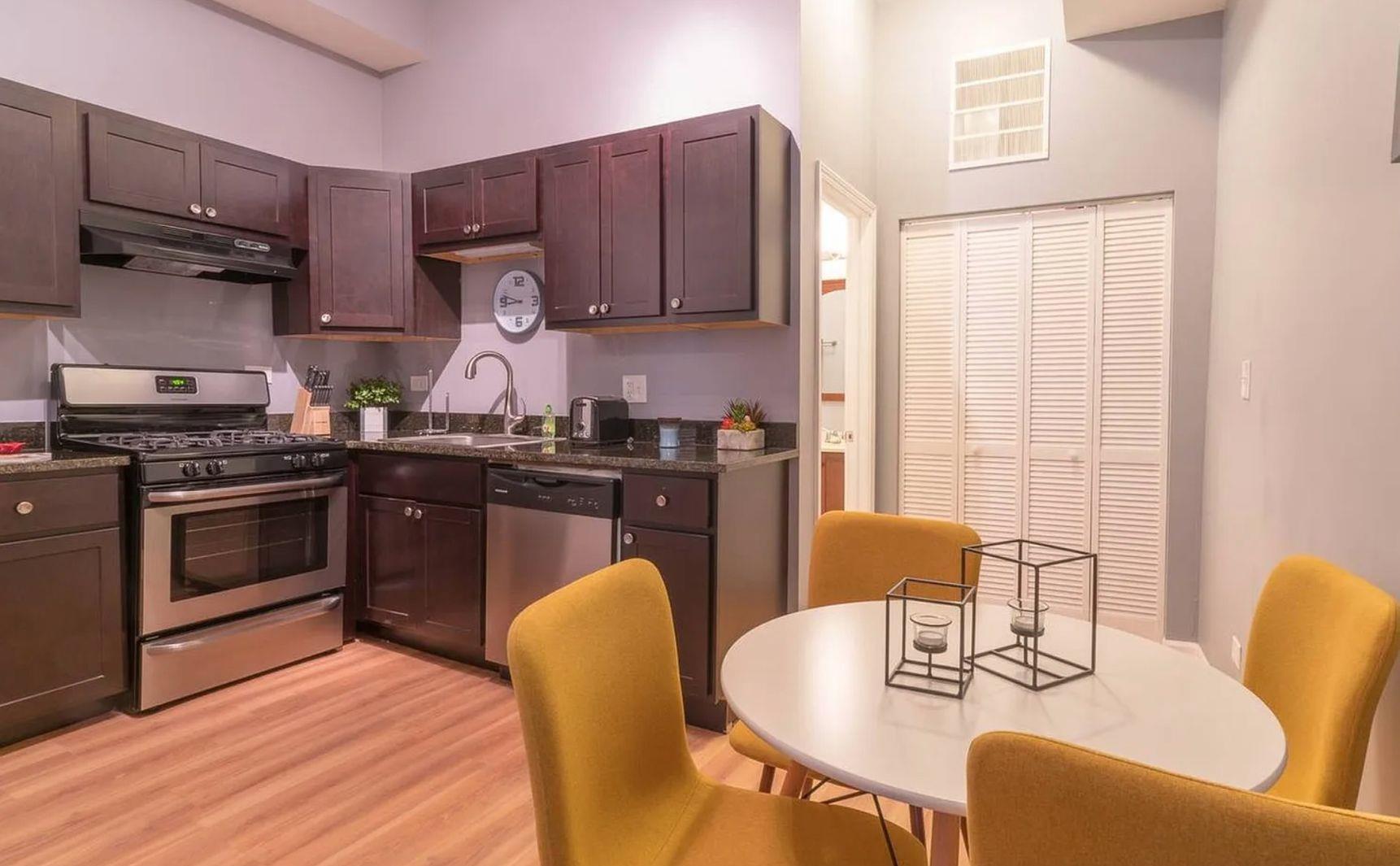 1140 West 18th Street Chicago, IL 60608 - Photo 3 of 5 a kitchen with stainless steel appliances granite countertop a stove a sink dishwasher a dining table and chairs with wooden floor